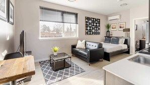 Una sala moderna con sofá, cama, mesa de comedor y zona de cocina.