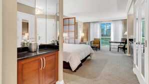 A hotel room with a bed, a desk, a chair, a kitchenette, and a large window. - MGM 1 Bedroom Balcony And Or Studio Luxury Suites (Las Vegas)