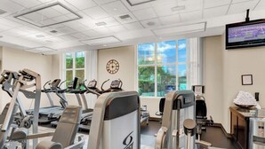 Ein Fitnessstudio mit Cardiogeräten, Krafttrainingsgeräten und einem Fernsehbildschirm.