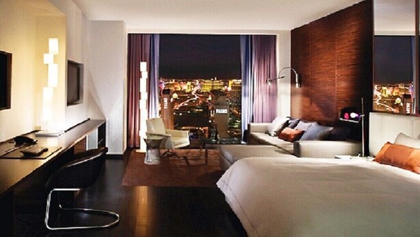 Een moderne hotelkamer met uitzicht op de stad, een bed, een bureau en een stoel.