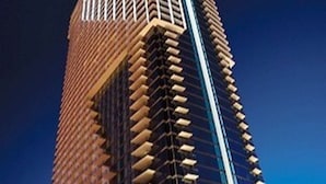 Een hoog gebouw met een uniek architectonisch ontwerp, met een reeks balkons en een opvallend verticaal element.