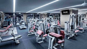 Een moderne sportschool met diverse fitnessapparaten, een bord waarop 