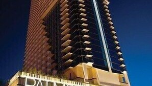 A tall, modern building with a unique architectural design, featuring a prominent "PALMS PLACE" sign at the base.