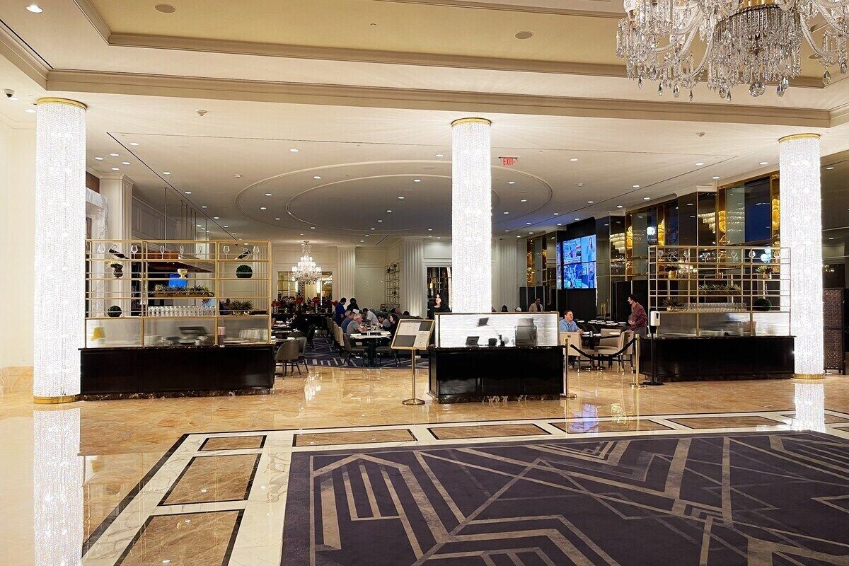A spacious lobby with high ceilings, a grand chandelier, and a central reception desk.