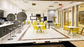 Un restaurant moderne avec des chaises et des tables jaunes, une cloison en verre et un panneau indiquant « Entrée réservée aux clients ».