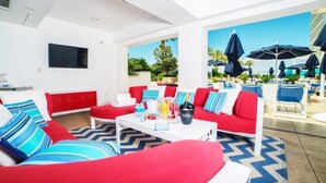 Une chambre d’hôtel moderne, décorée dans des tons de rouge et de bleu, équipée d’un téléviseur à écran plat et offrant une vue sur l’espace extérieur de la piscine.