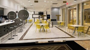 Un restaurant moderne avec des chaises et des tables jaunes, une cloison en verre et un panneau indiquant « Entrée réservée aux clients ».