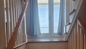 A staircase with wooden steps and white railings, leading to a door with a view of the outdoors. - Spacious Beach Home - Steps to Ocean, Dining & Entertainment (Salisbury)