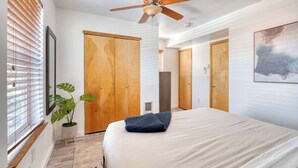 A bedroom with a bed, wooden wardrobe, ceiling fan, potted plant, and a painting on the wall. - Modern 3BR + sofa bed• Alberta Arts • WalkScore 99 (Portland)