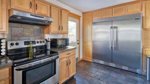 A kitchen with wooden cabinets, a stainless steel refrigerator, a microwave, and a stove. - Modern 3BR + sofa bed• Alberta Arts • WalkScore 99 (Portland)