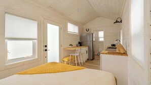 Una camera accogliente e compatta con un letto, un piccolo angolo ristoro e angolo cottura.
