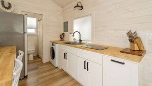 Una cucina compatta con mobili in legno, un lavandino, un frigorifero e una lavatrice.