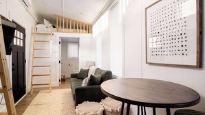 A modern, well-lit room with a bunk bed, a round table, and a large framed artwork on the wall. - Tiny Retreat • Walk to Bars, Food & Local Art (Portland)
