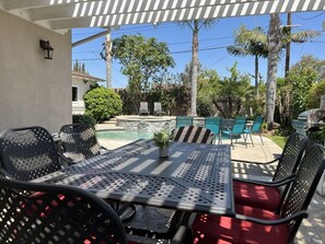 An outdoor patio with a table and chairs, a pool, and palm trees. - Awesome 4 Bedroom, 3 1/2 Bath Home 1/2 Mile Walk To Disney (Anaheim)