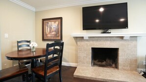 A dining area with a table and chairs, a fireplace, a mounted television, and a framed picture on the wall. - Awesome 4 Bedroom, 3 1/2 Bath Home 1/2 Mile Walk To Disney (Anaheim)