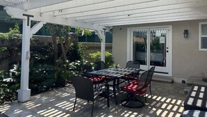 An outdoor patio with a covered table and chairs, a pergola, and a door leading to a covered area. - Awesome 4 Bedroom, 3 1/2 Bath Home 1/2 Mile Walk To Disney (Anaheim)