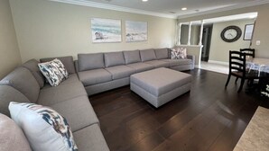 A living room with a sectional sofa, ottoman, and a dining area with a table and chairs. - Awesome 4 Bedroom, 3 1/2 Bath Home 1/2 Mile Walk To Disney (Anaheim)