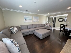 A living room with a sectional sofa, ottoman, and a dining area with a table and chairs. - Awesome 4 Bedroom, 3 1/2 Bath Home 1/2 Mile Walk To Disney (Anaheim)