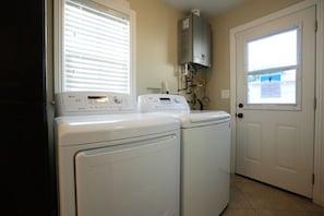 A laundry room with two front-loading washers and dryers, a water heater, and a door with a window. - Awesome 4 Bedroom, 3 1/2 Bath Home 1/2 Mile Walk To Disney (Anaheim)