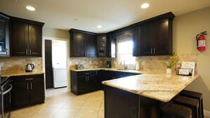 A kitchen with dark cabinets, a granite countertop, and a fire extinguisher on the wall. - Awesome 4 Bedroom, 3 1/2 Bath Home 1/2 Mile Walk To Disney (Anaheim)
