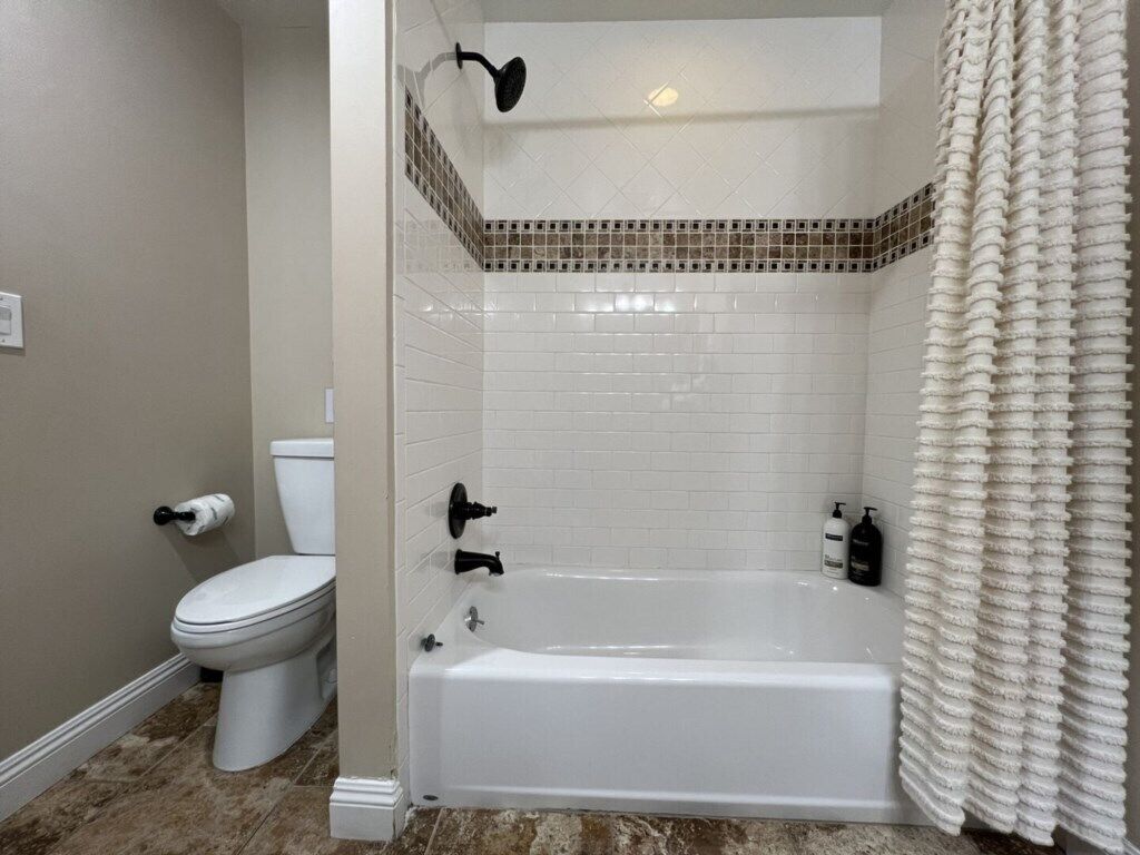 A bathroom with a white bathtub, a toilet, and a shower curtain.