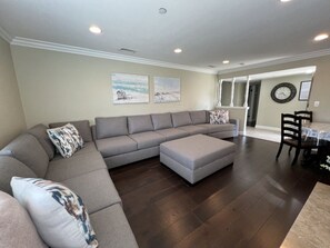 A living room with a sectional sofa, ottoman, and a dining area with a table and chairs. - Awesome 4 Bedroom, 3 1/2 Bath Home 1/2 Mile Walk To Disney (Anaheim)