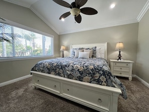 A bedroom with a bed, nightstands, a ceiling fan, and a window with blinds.