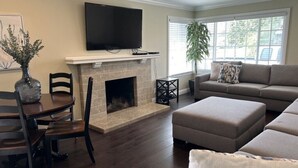 A living room with a fireplace, a sofa, a TV, and a dining table. - Awesome 4 Bedroom, 3 1/2 Bath Home 1/2 Mile Walk To Disney (Anaheim)