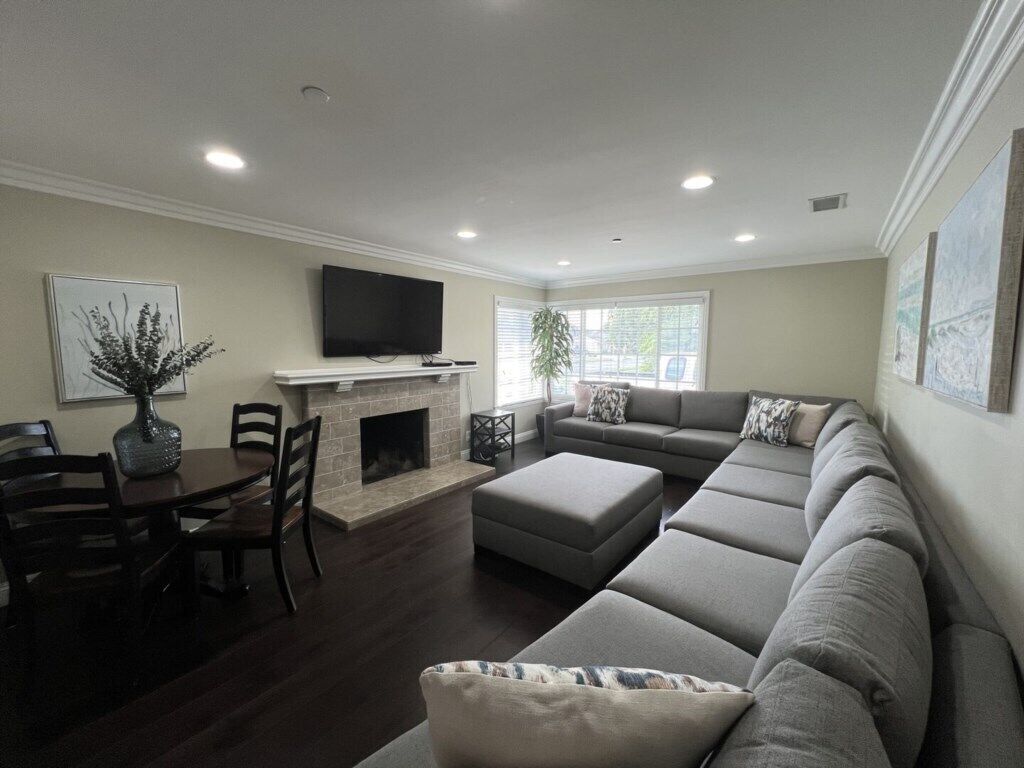 A living room with a fireplace, a sofa, a television, and a dining area.
