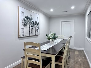 A dining room with a long table, chairs, a vase with flowers, and a framed picture on the wall. - Spectacular 5 Bedroom, 4 Bath Pool Home Near Disney (Anaheim)