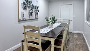 A dining room with a long table, chairs, a vase with flowers, and a framed picture on the wall. - Spectacular 5 Bedroom, 4 Bath Pool Home Near Disney (Anaheim)