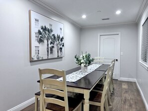 A dining room with a long table, chairs, a vase with flowers, and a framed picture on the wall. - Spectacular 5 Bedroom, 4 Bath Pool Home Near Disney (Anaheim)