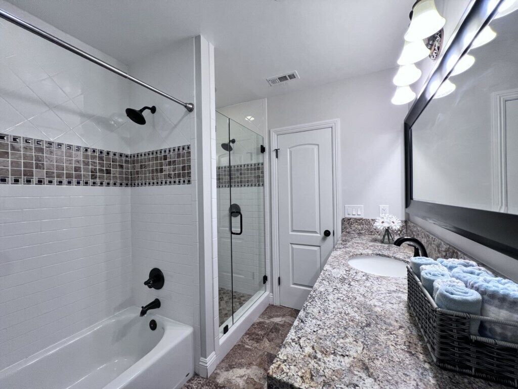 A bathroom with a bathtub, a glass-enclosed shower, a sink, and a mirror.