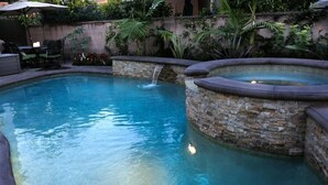 A swimming pool with a waterfall feature and stone walls. - Spectacular 5 Bedroom, 4 Bath Pool Home Near Disney (Anaheim)