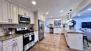 A modern kitchen with white cabinetry, stainless steel appliances, and a wooden floor. - Spectacular 5 Bedroom, 4 Bath Pool Home Near Disney (Anaheim)