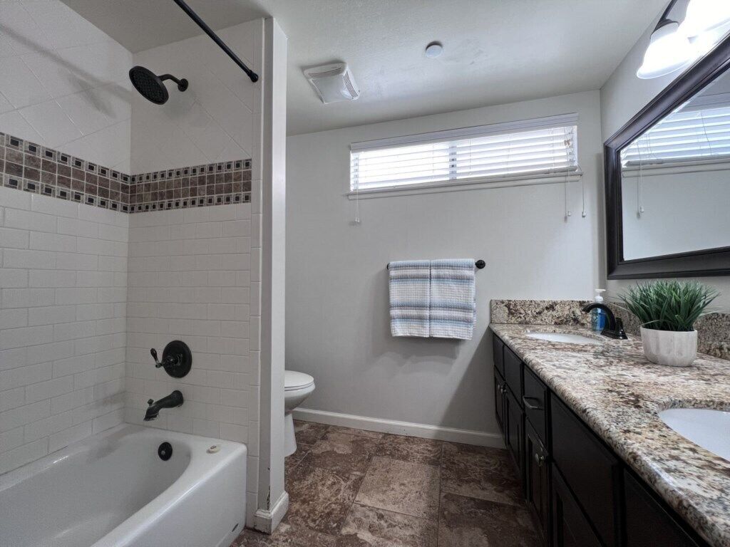 Une salle de bain équipée d’une baignoire, de toilettes, d’une douche et d’un meuble-lavabo avec un évier et un plan de travail.