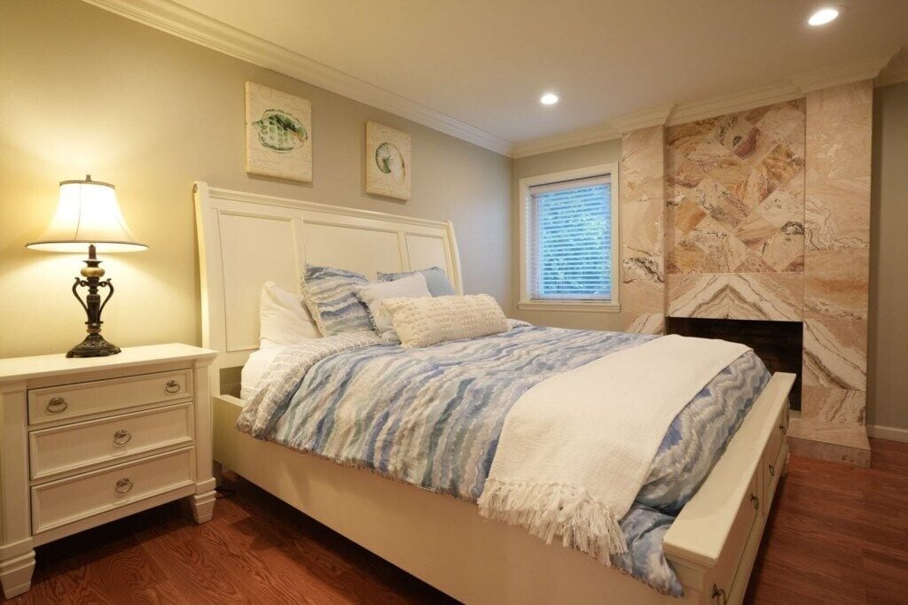 Ett sovrum med en säng, ett nattduksbord, en lampa och konstverk på väggen.