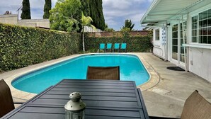 A covered outdoor area with a swimming pool, a table with chairs, and a lamp. - Large Family Pool Home 2.5 Miles To Disney w/3 King Beds!!! (Anaheim)