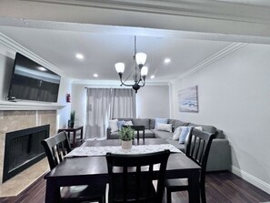 A dining area with a table, chairs, a chandelier, a television, and a sofa. - Luxurious 2 Bedroom Condo Shortest Walk To Disney (Anaheim)