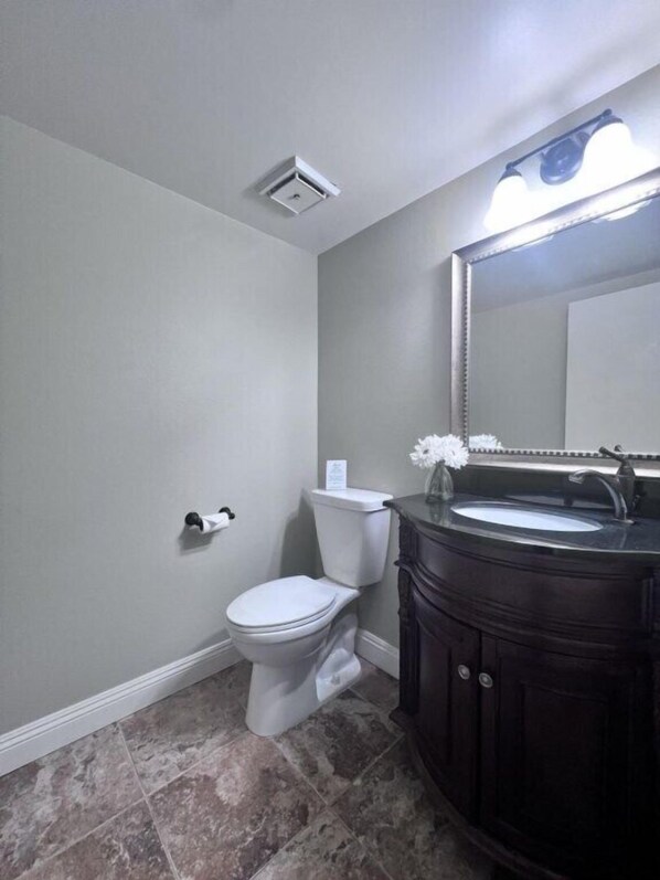 A bathroom with a toilet, sink, mirror, and a ceiling light fixture. - Luxurious 2 Bedroom Condo Shortest Walk To Disney (Anaheim)
