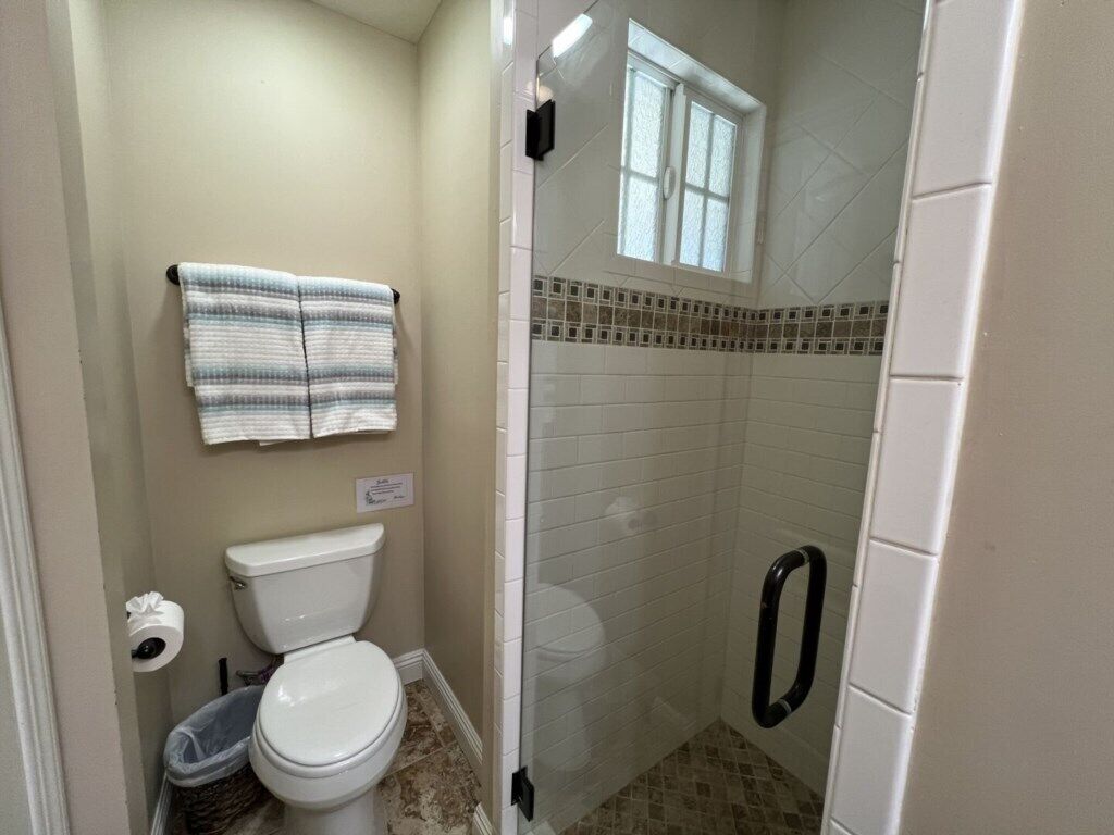 Une salle de bain avec des toilettes, un espace douche et une fenêtre.