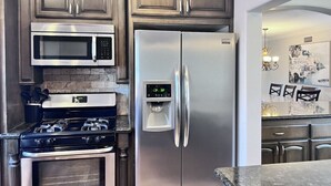 Una cocina con electrodomésticos de acero inoxidable, armarios de madera y encimera de mármol.