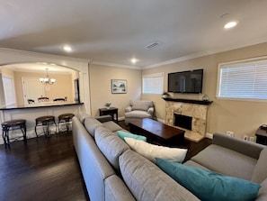 A living room with a sofa, a fireplace, a television, and a dining area with chairs and a table.