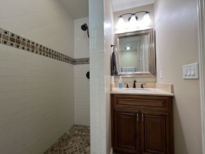 A bathroom with a shower, a sink with a mirror, and a towel rack. - Gorgeous Pool Home 1/2 Mile Walk to Disney (Anaheim)