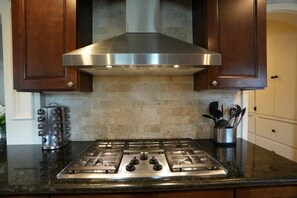 A kitchen with a stainless steel range hood, a gas stove, and a backsplash of beige tiles. - Incredible Estate 5 Bedrooms 3 Bathroom W/resort Style Rock Pool & Jacuzzi (Fullerton)