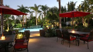 An outdoor patio area with a pool, surrounded by palm trees and tropical plants. - Incredible Estate 5 Bedrooms 3 Bathroom W/resort Style Rock Pool & Jacuzzi (Fullerton)