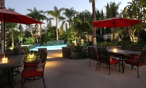 An outdoor patio area with a pool, surrounded by palm trees and tropical plants. - Incredible Estate 5 Bedrooms 3 Bathroom W/resort Style Rock Pool & Jacuzzi (Fullerton)