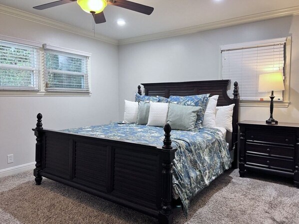 A bedroom with a dark wooden bed, a ceiling fan, and a nightstand with a lamp.