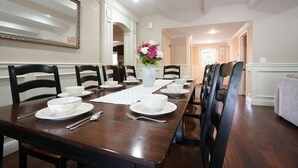 A dining room with a long table set for a meal, chairs, a vase with flowers, and a mirror on the wall. - Incredible Estate 5 Bedrooms 3 Bathroom W/resort Style Rock Pool & Jacuzzi (Fullerton)