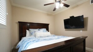 A bedroom with a bed, a ceiling fan, a TV mounted on the wall, and a carpeted floor. - Incredible Estate 5 Bedrooms 3 Bathroom W/resort Style Rock Pool & Jacuzzi (Fullerton)
